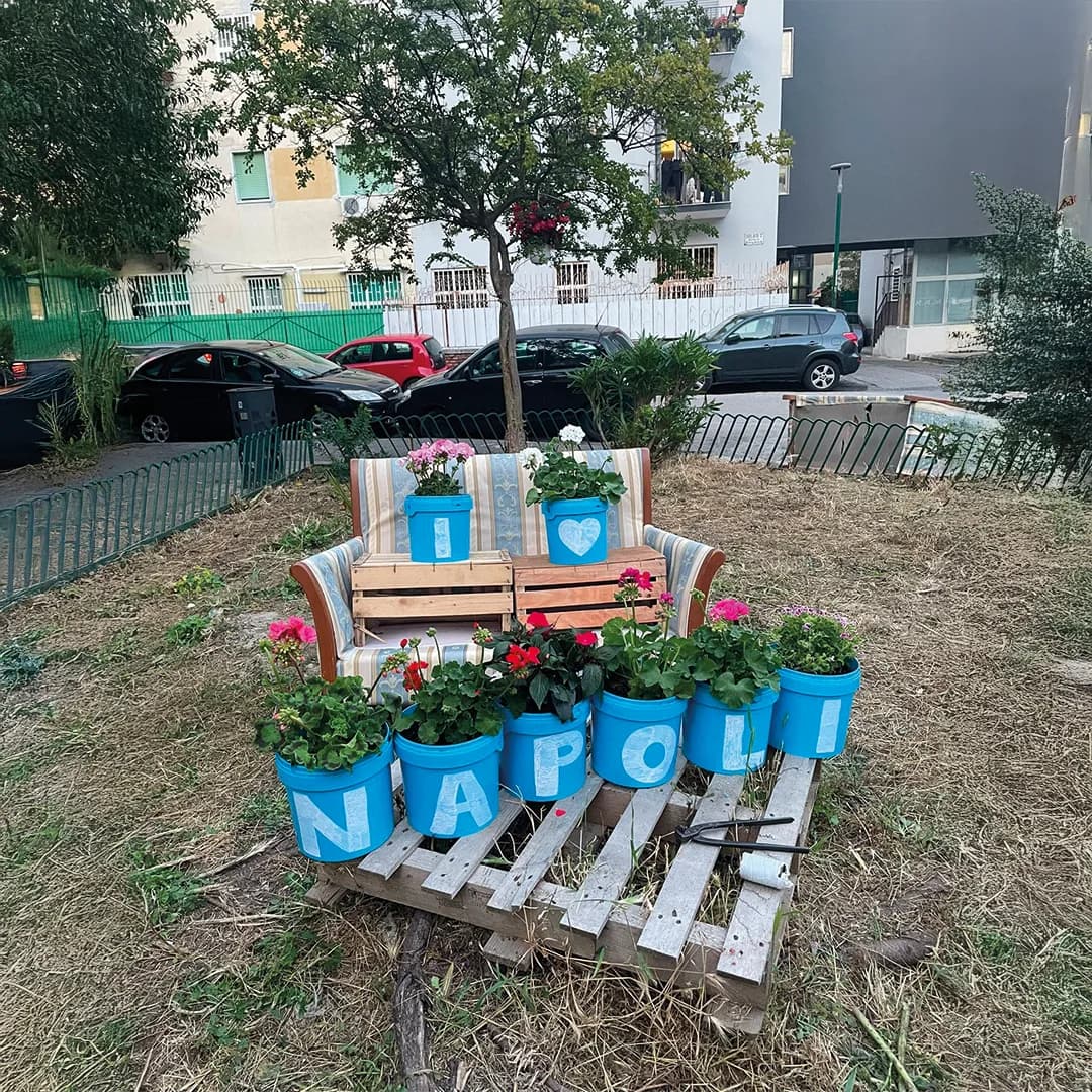 L’aiuola dell’associazione: una poltrona e un bancale riciclati con vasi azzurri di gerani che compongono la scritta «I ♥ Napoli»